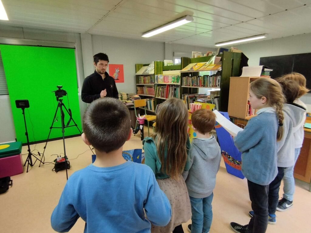 Gwenolé Robert animant un atelier de réalisation vidéo sur fond vert avec des scolaires.
