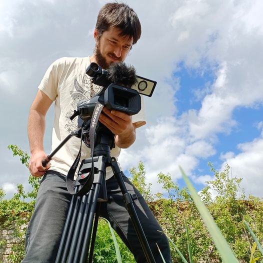Gwenolé Robert, vidéaste, ajustant sa caméra sur trépied en plein tournage.